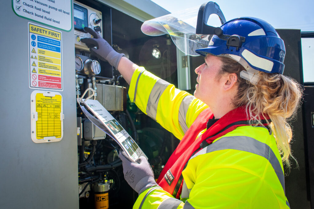 Operative in hi-vis and blue helmet starting a 8' water pump